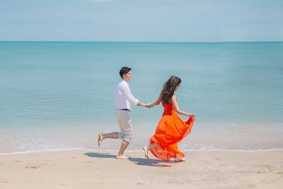 Couple Walking Barefoot by the Beach
